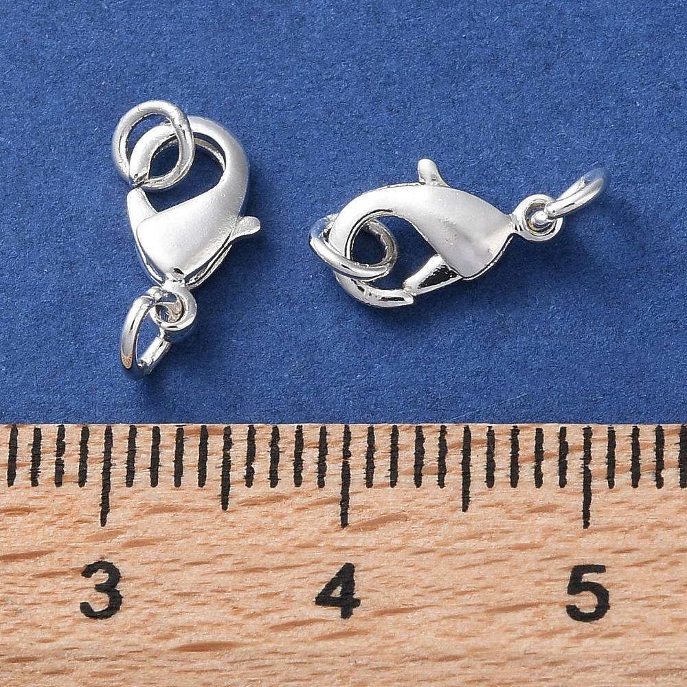 2 anti tarnish plated jewelry clasps with rings for the purpose of making a closure on a necklace or bracelet on a blue background with a wood ruler for size comparison