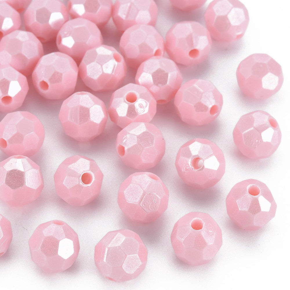 Pink faceted round beads with a central hole, scattered on a plain white background.