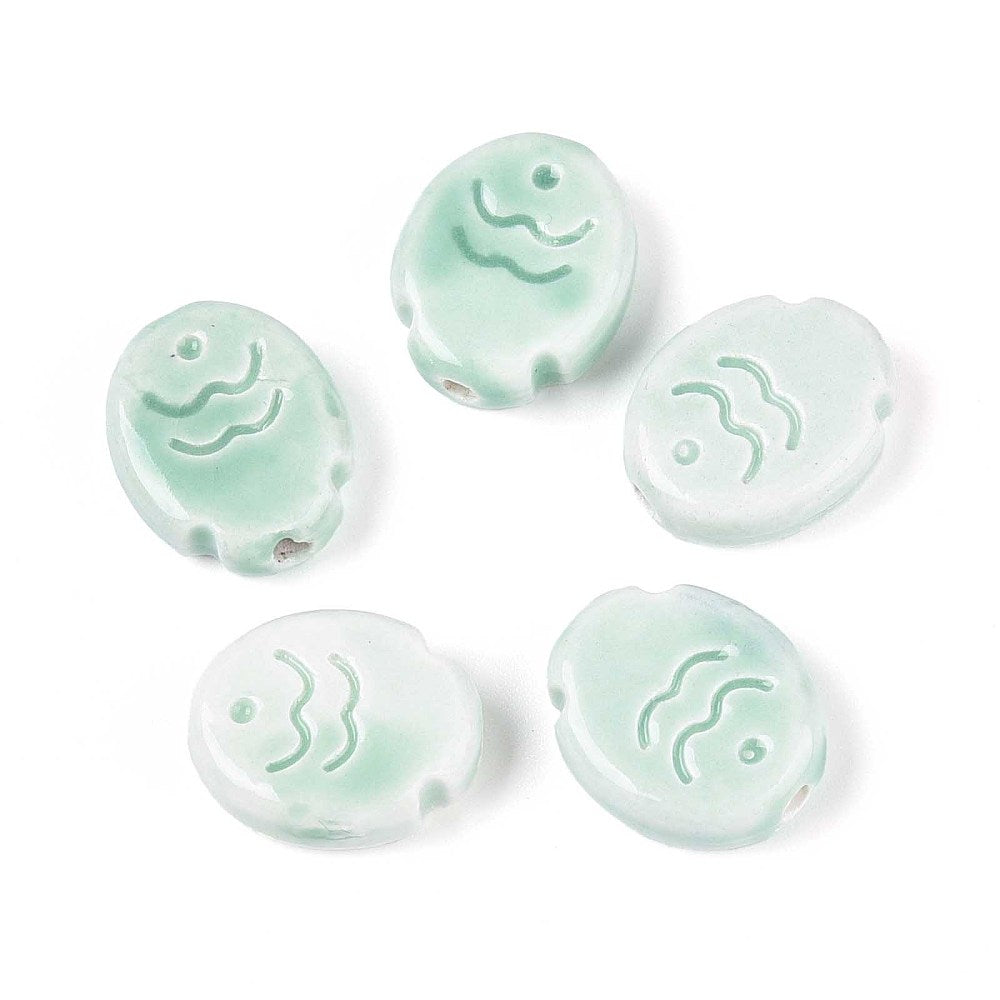 Five pink ceramic fish beads with wave designs on a white background.