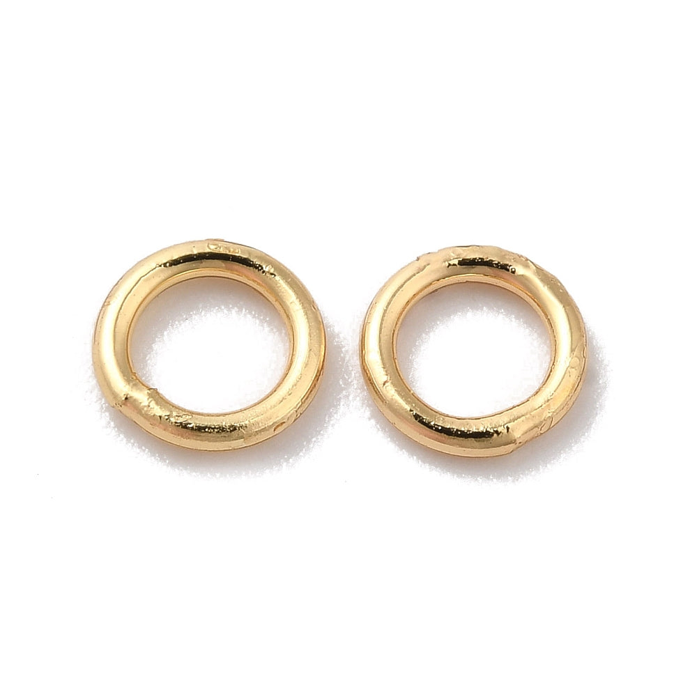 Pair of gold closed soldered jump rings on a white background