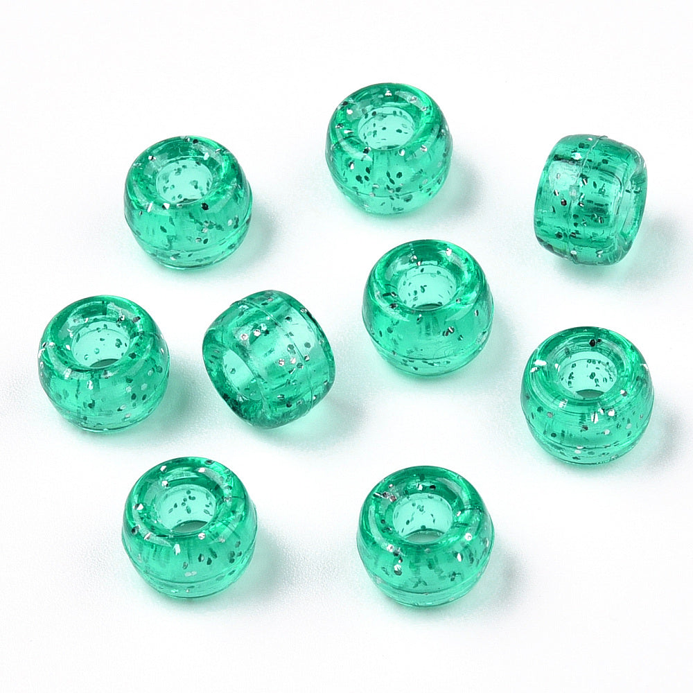 A close-up image of green teal glitter transparent acrylic pony beads with a visible hole in the center for stringing purposes.