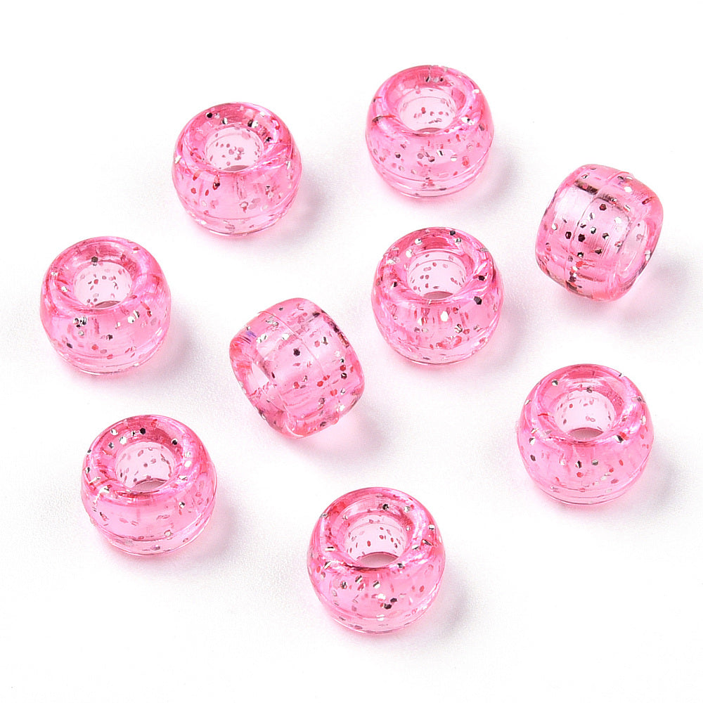 A close-up image of light pink glitter transparent acrylic pony beads with a visible hole in the center for stringing purposes.