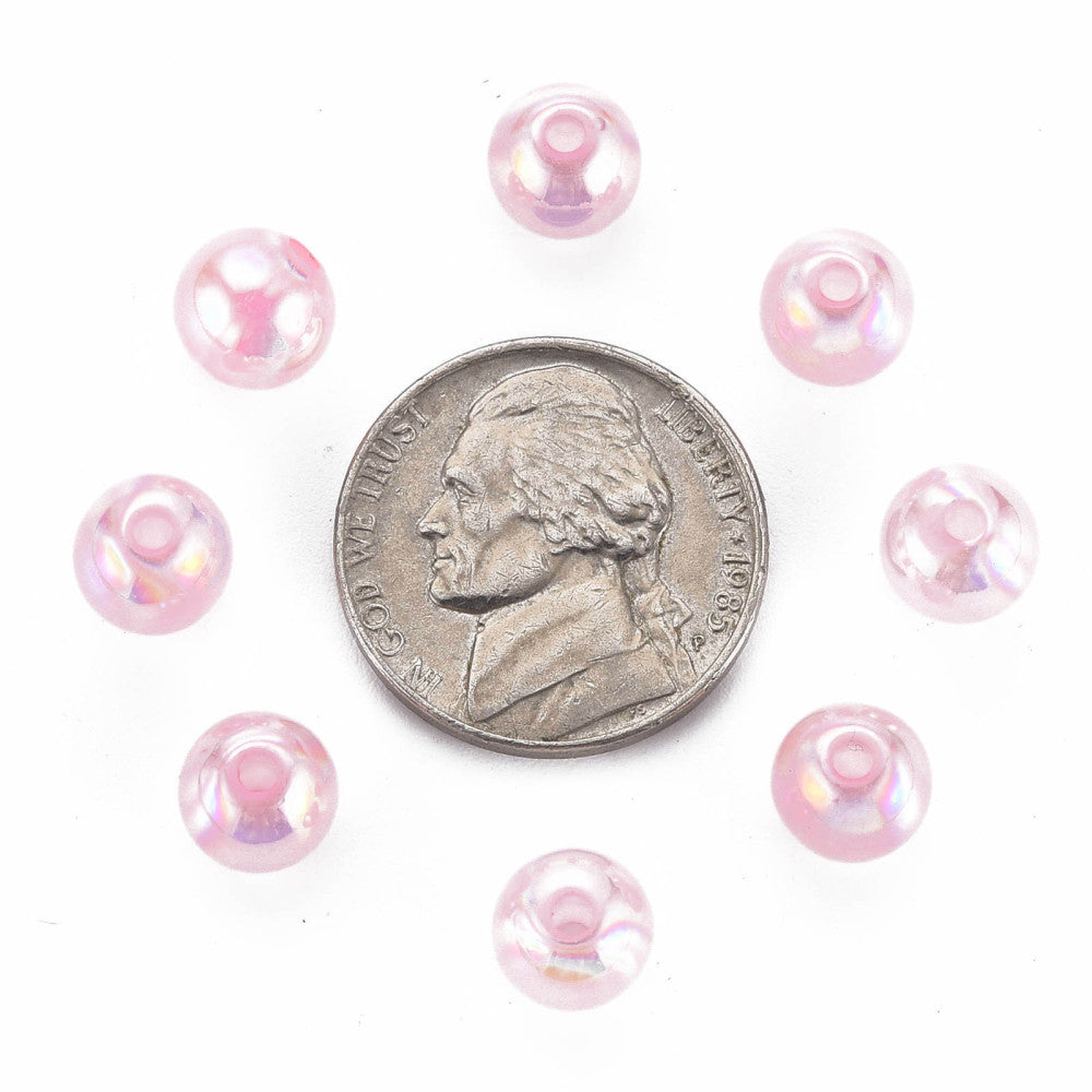 Pink beads arranged around a dime on a white background