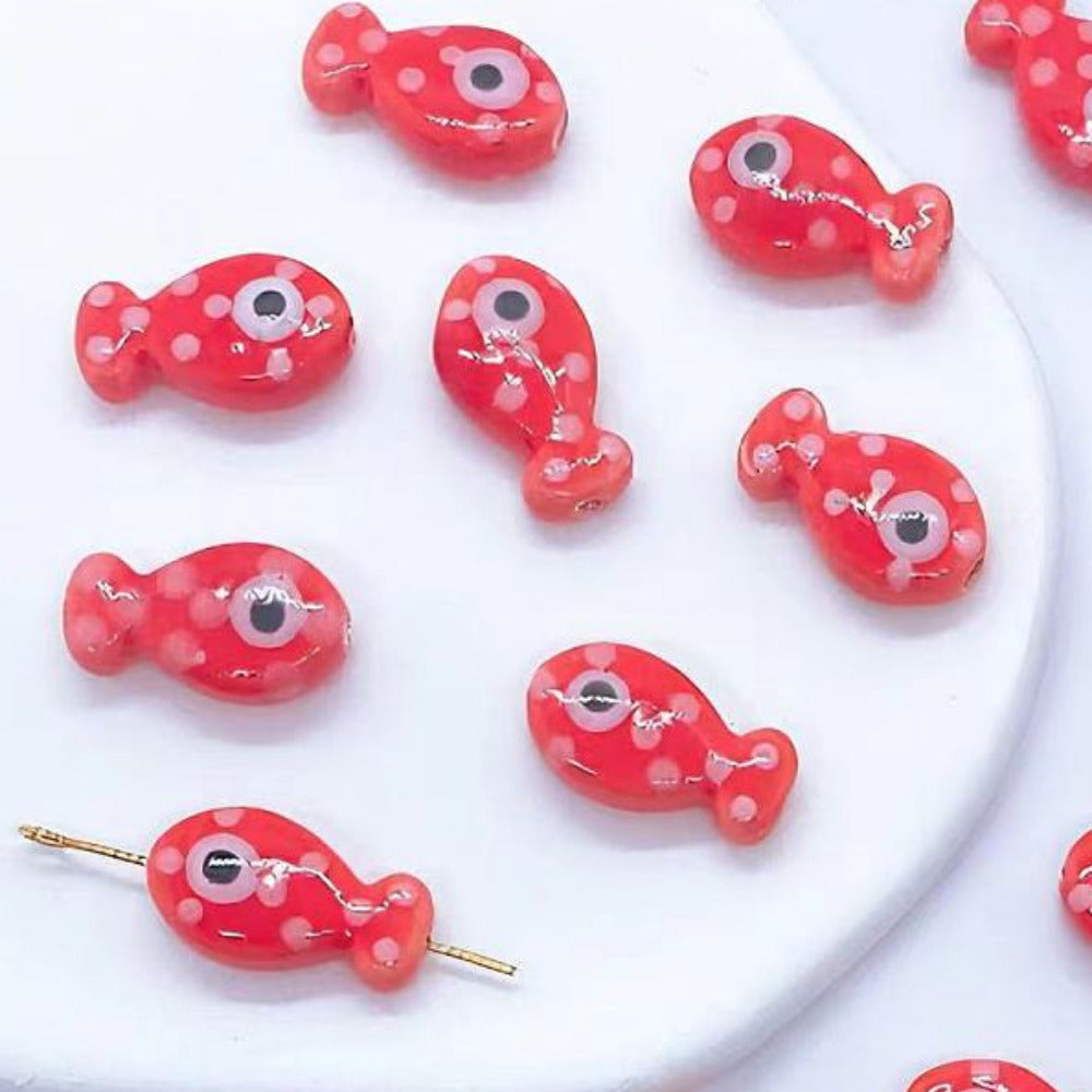Red fish-shaped bead art decorations with white polka dots on a white background.