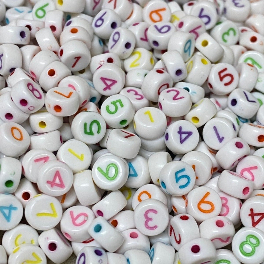 A collection of white round acrylic beads each with a different number from 0 to 9 written in various colors.