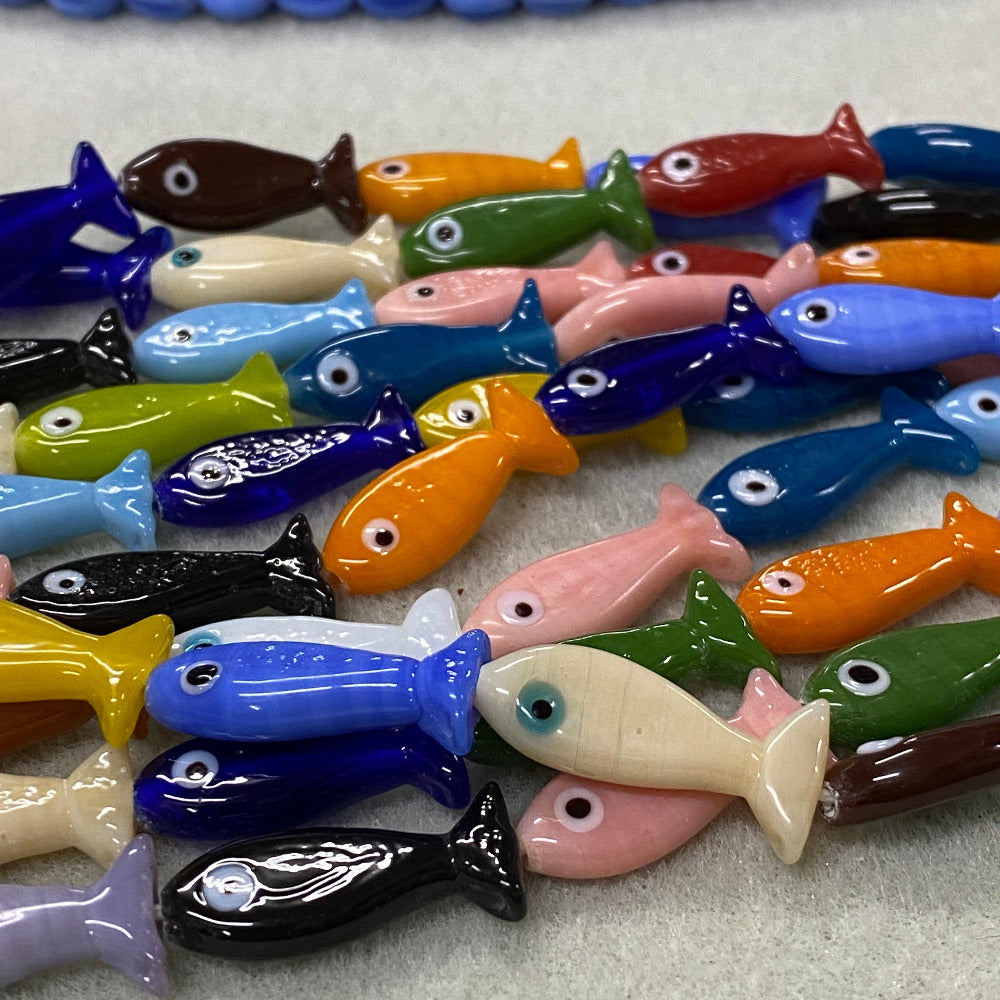Colorful fish-shaped beads on a textured surface
