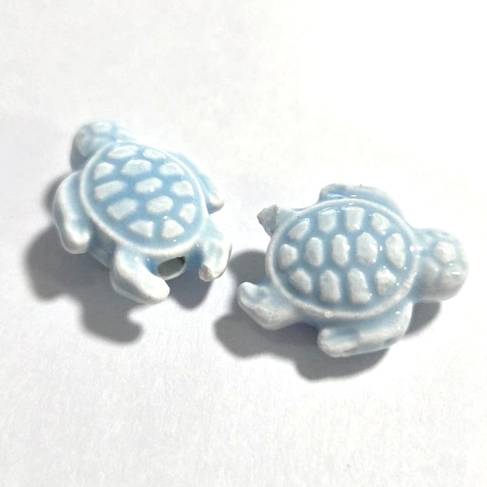 Two ceramic turtle beads on a white background