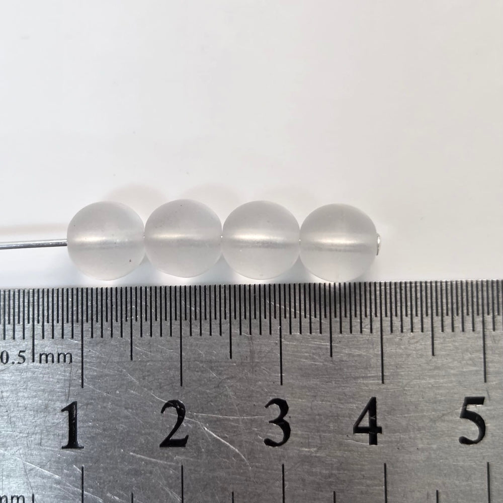 Four clear beads on a ruler for size reference