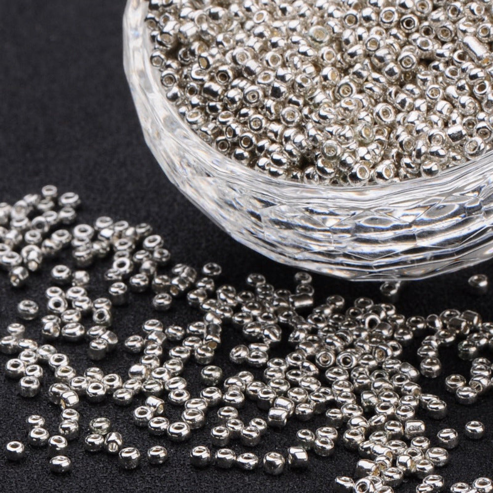 Silver beads in a clear glass container on a black background