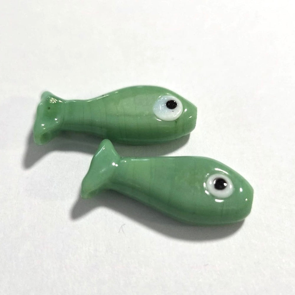 Two green ceramic fish-shaped objects on a white background