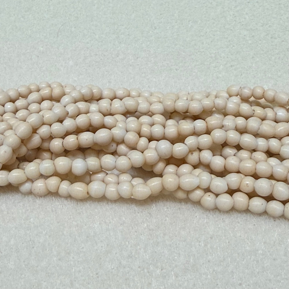 Strings of creaam round beads on a light gray background