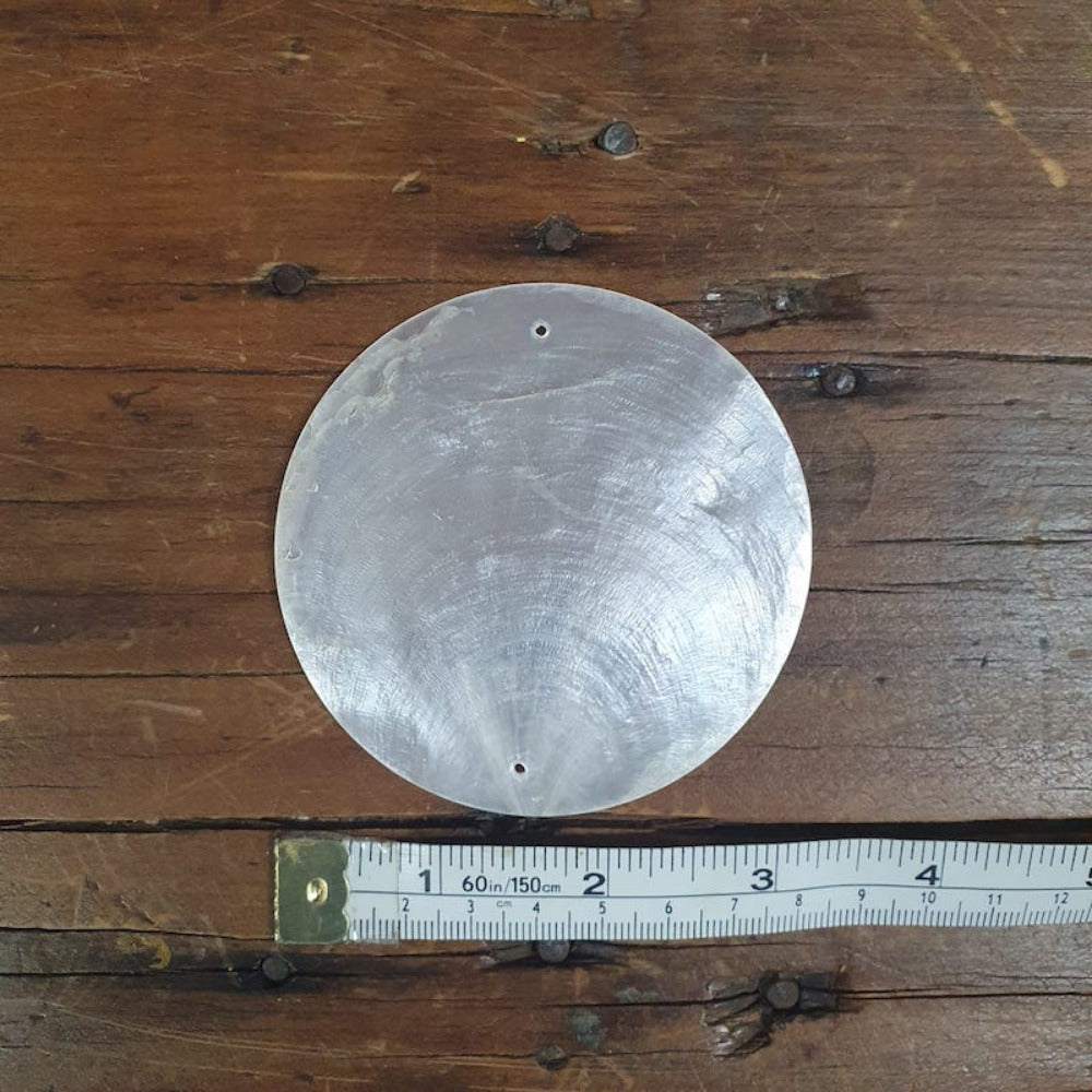 white capiz shell on a wooden surface with a tape measure to show size used for wedding name cards, hanging decorations and craft items