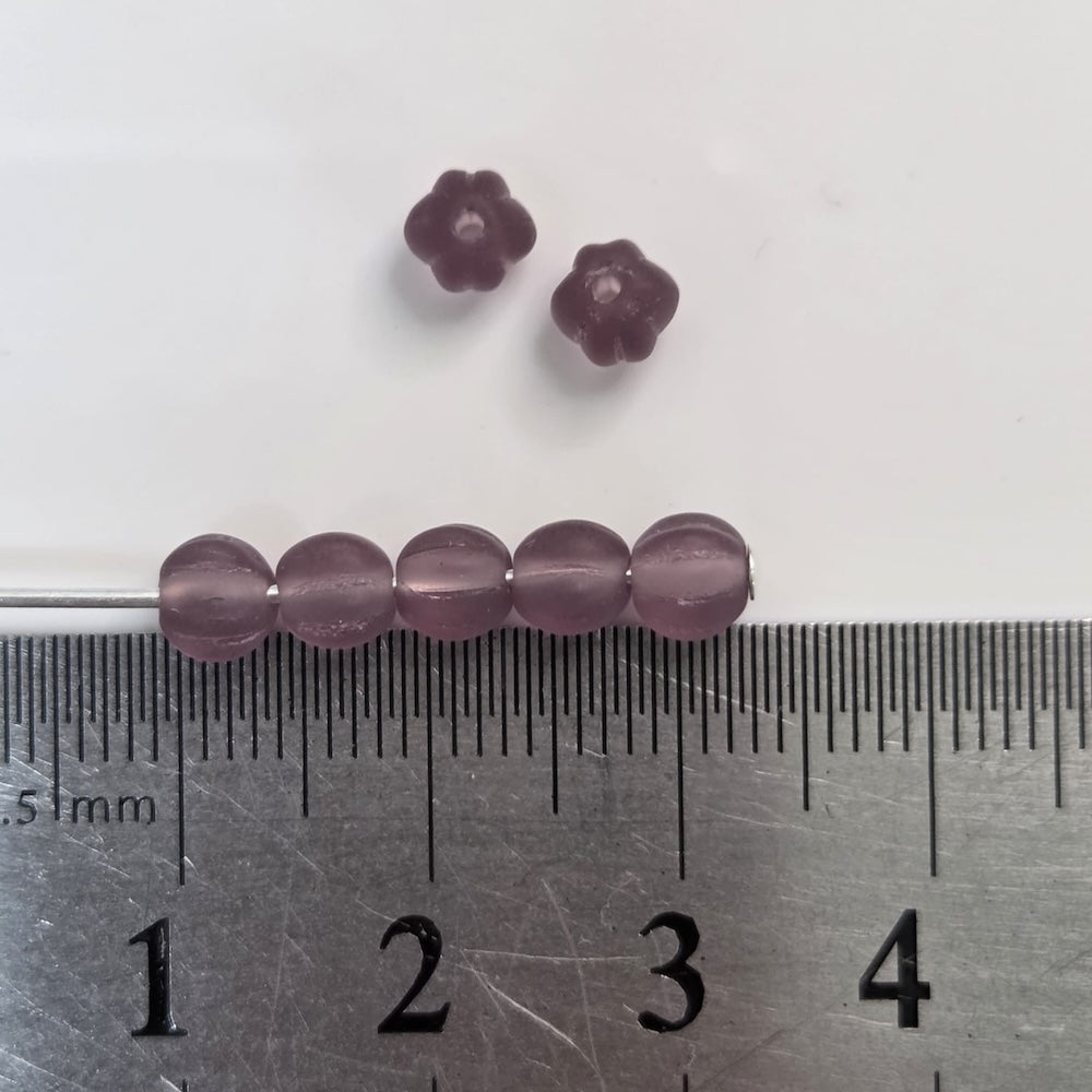 Purple beads on a ruler for size reference