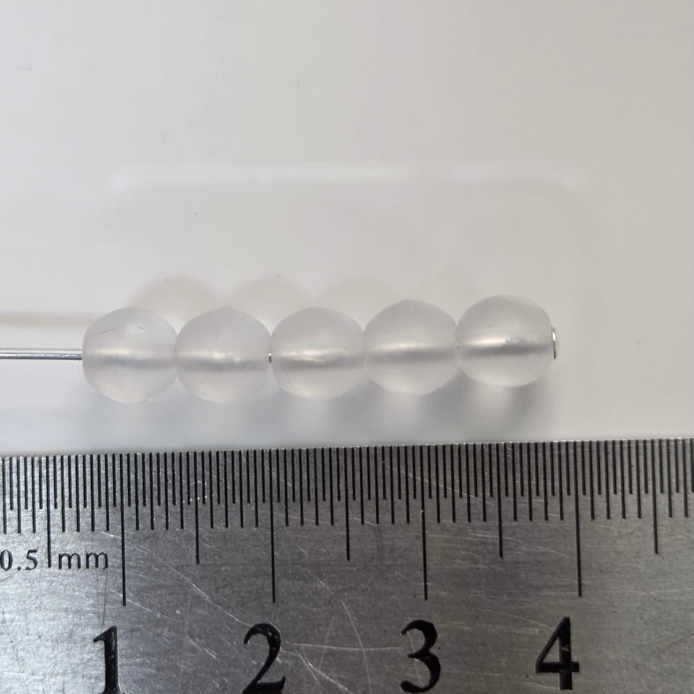 matte transparent glass round beads on a pin with a ruler to show size