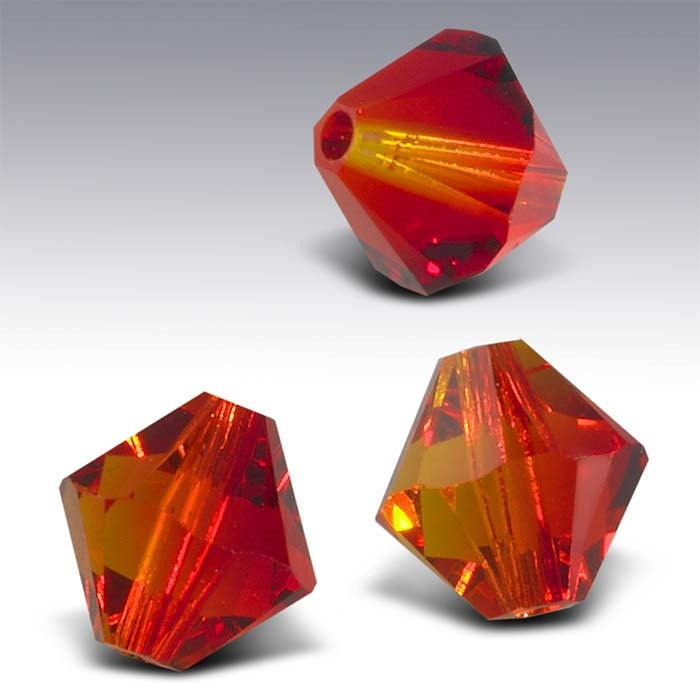 Three red-orange faceted crystal beads on a gray background