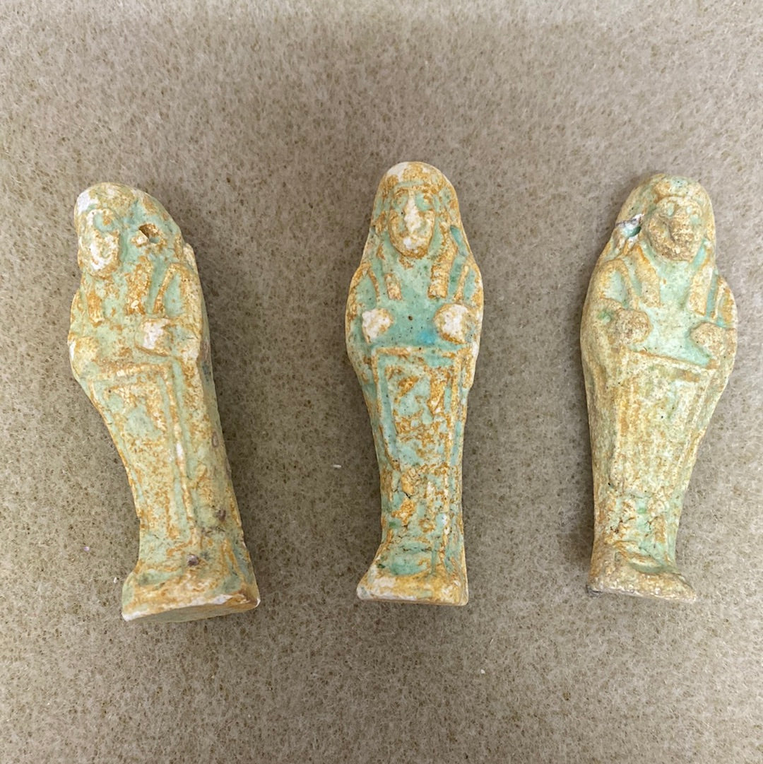 Three vintage Egyptian faience beads with blue and green colors, showing human-like figures.