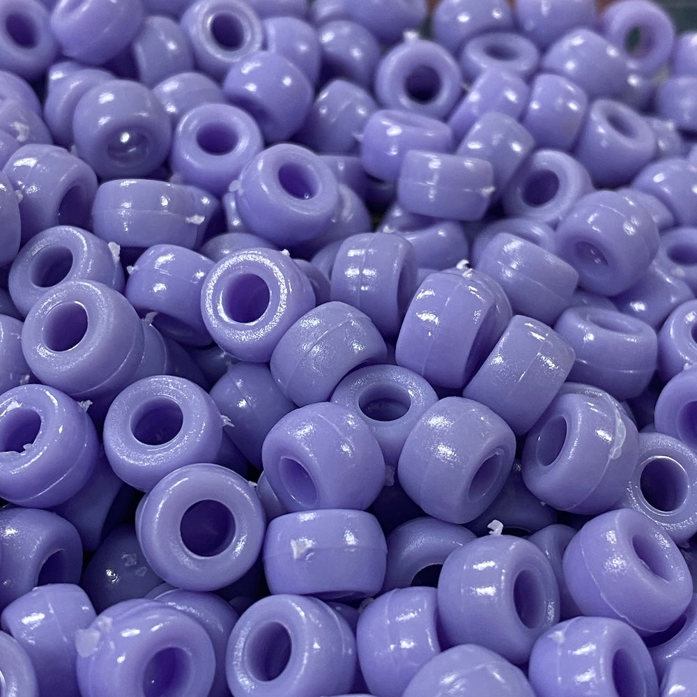 A close-up image of light purple opaque acrylic pony beads with a visible hole in the center for stringing purposes.