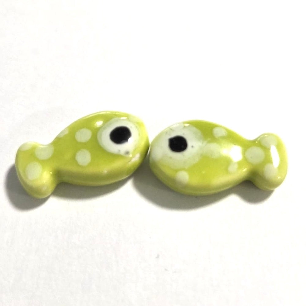 two lime green ceramic fish beads with white polka dots and black eyes
