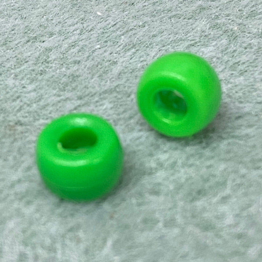 close up of 2 large holed acrylic beads used for craft and jewelry making on a textured grey background
