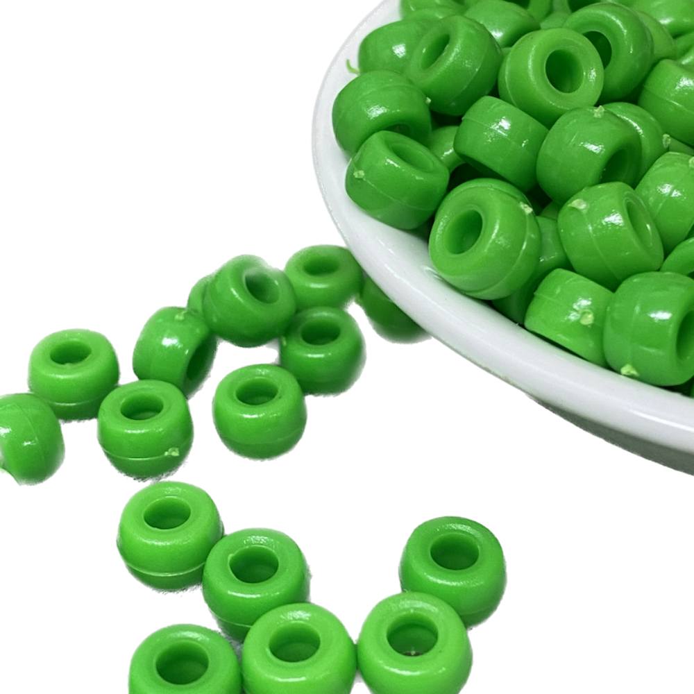 large hole plastic pony beads for the purpose of making craft and jewelry displayed in a bowl on a black surface