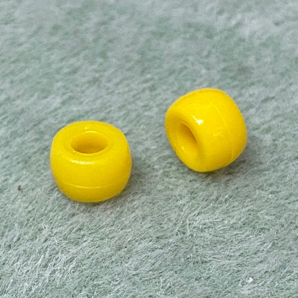 close up of 2 large holed acrylic beads used for craft and jewelry making on a textured background