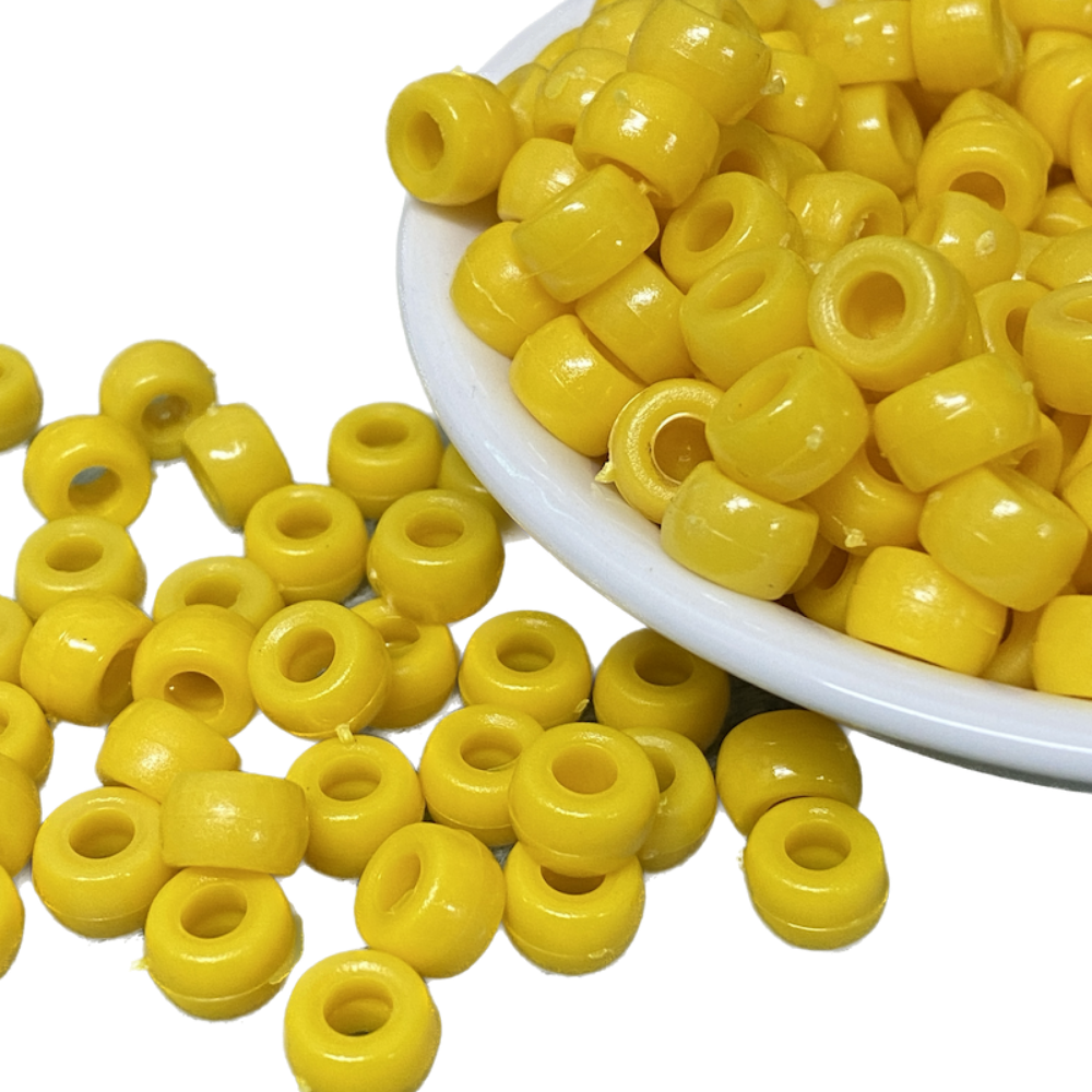 large hole plastic pony beads for the purpose of making craft and jewelry displayed in a bowl on a white surface