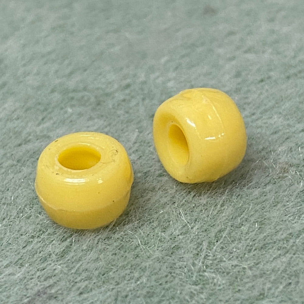 close up of 2 large holed acrylic beads used for craft and jewelry making on a textured background