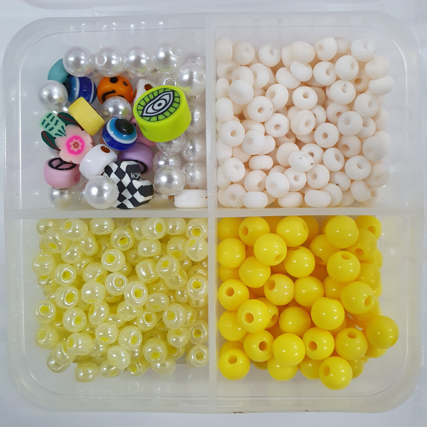 Assorted beads in a clear plastic container on a white background