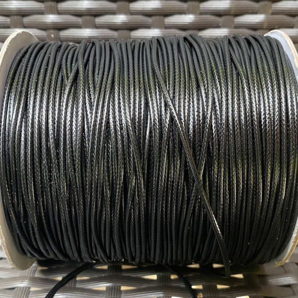 A spool of black waxed cord used for crafting and jewelry making.