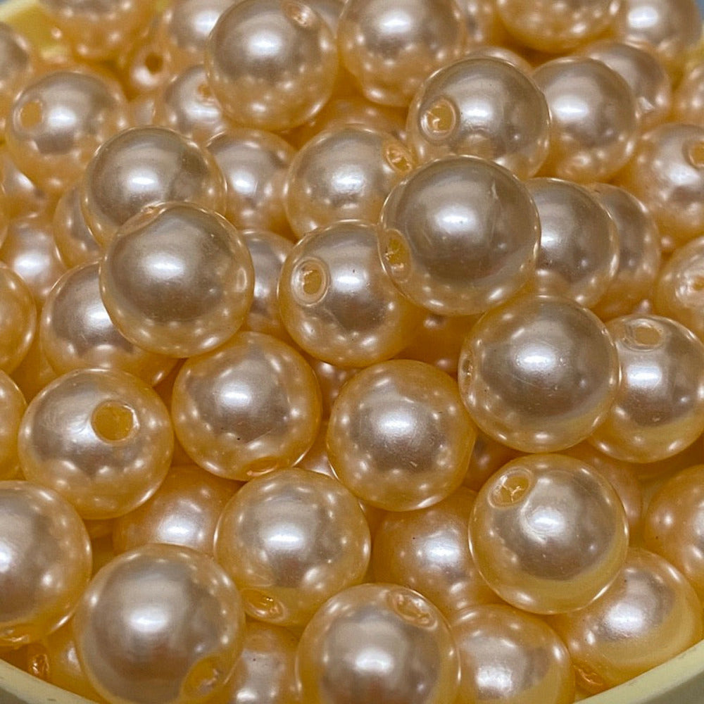A strand of round vintage acrylic pearl beads in a cream color, displayed in a bowl.