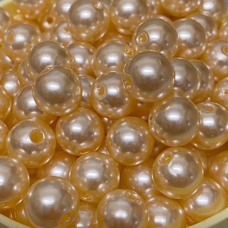 A collection of round vintage acrylic pearl beads in a cream color, stranded together.