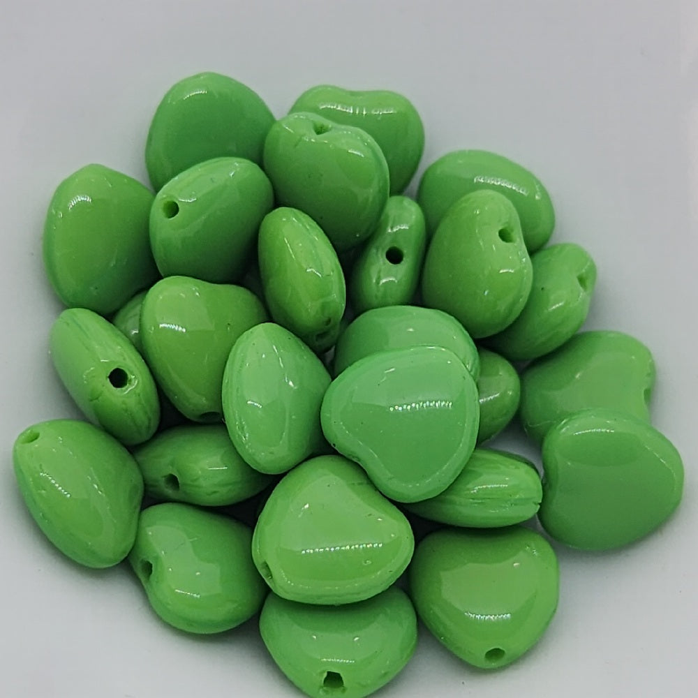 apple green heart beads in a white bowl showing threading holes for making jewelry