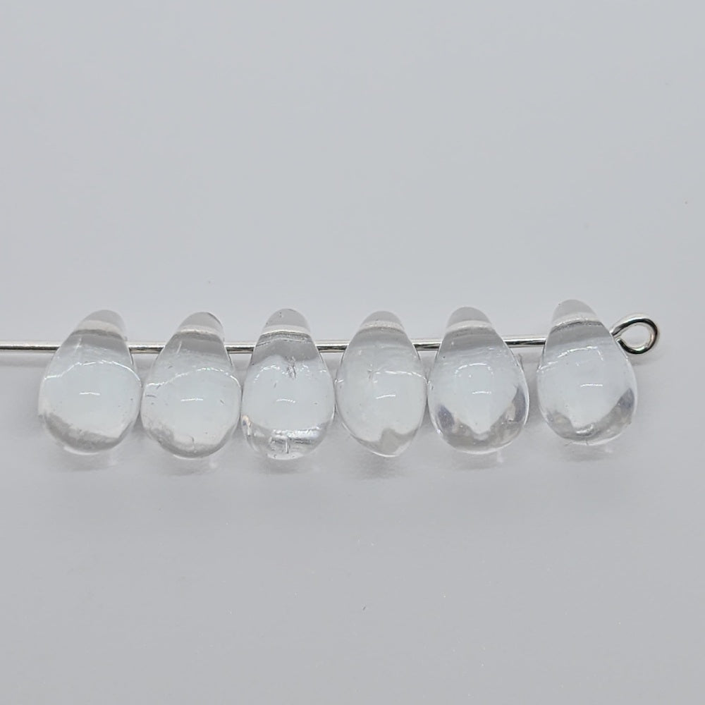 clear teardrop beads on a pin to show the threading hole on a grey background