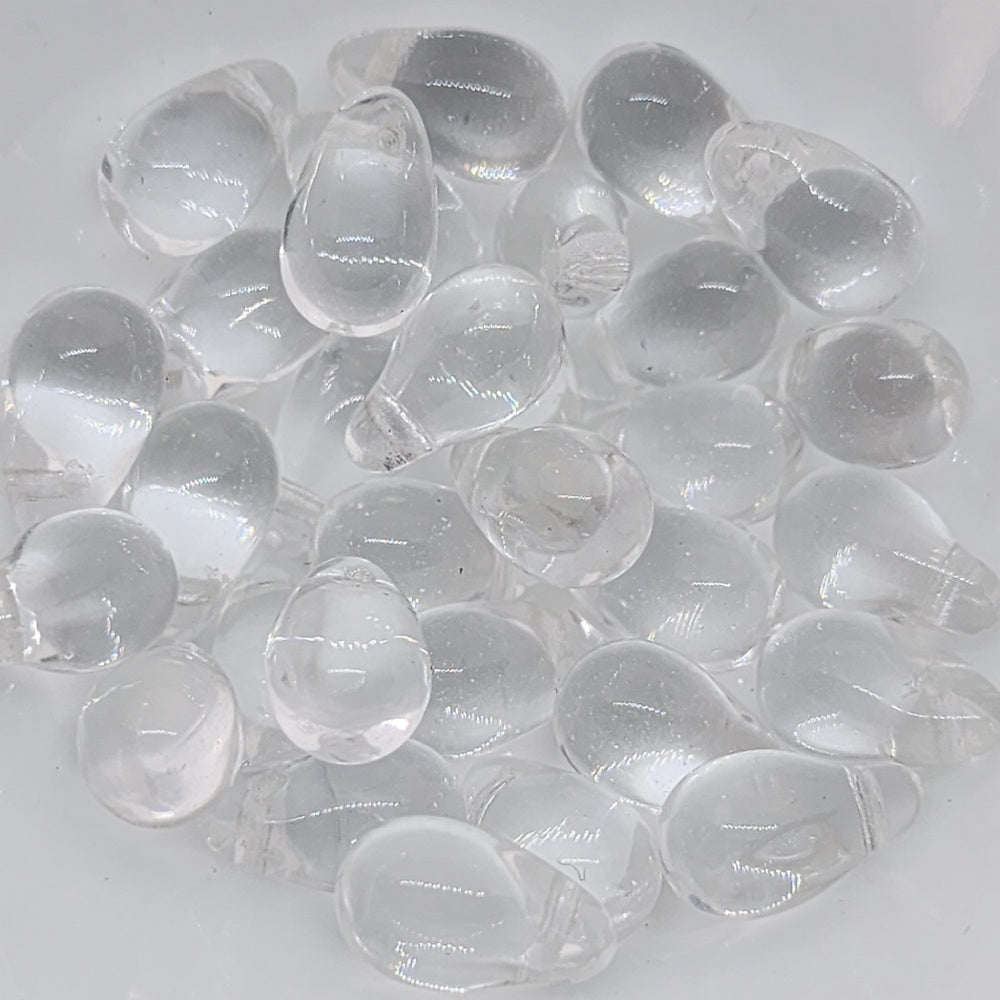A collection of clear, teardrop-shaped Czech glass beads.