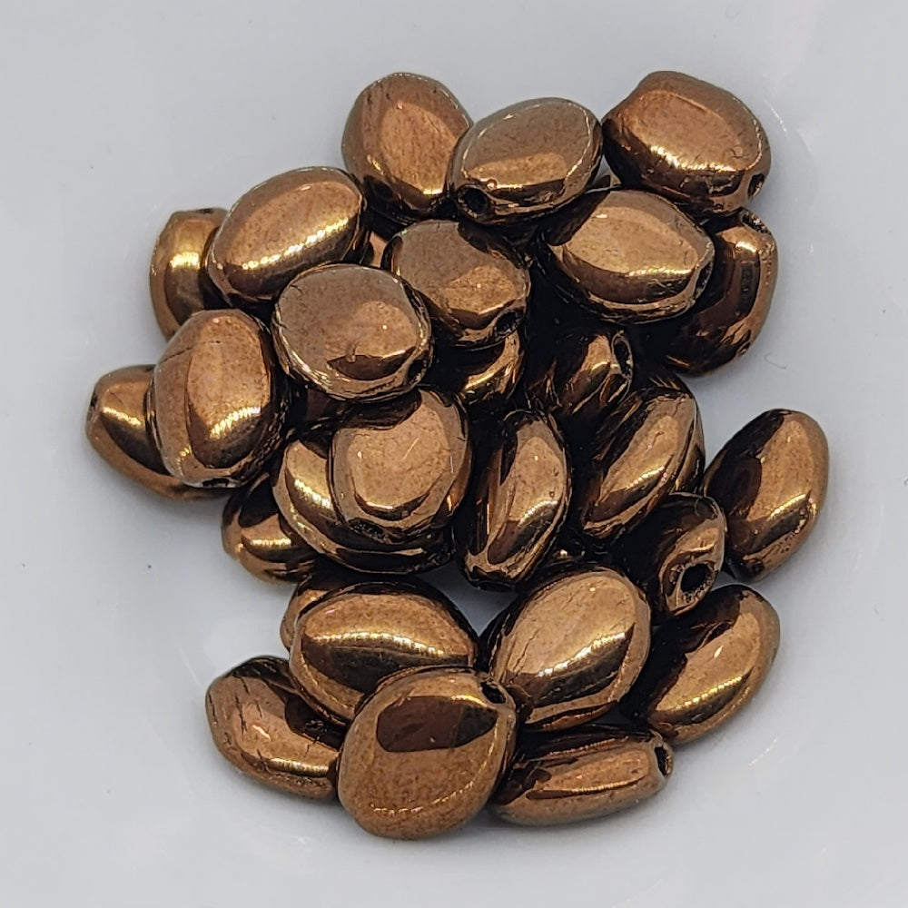 lustrous bronze oval flat beads in a group on a grey surface