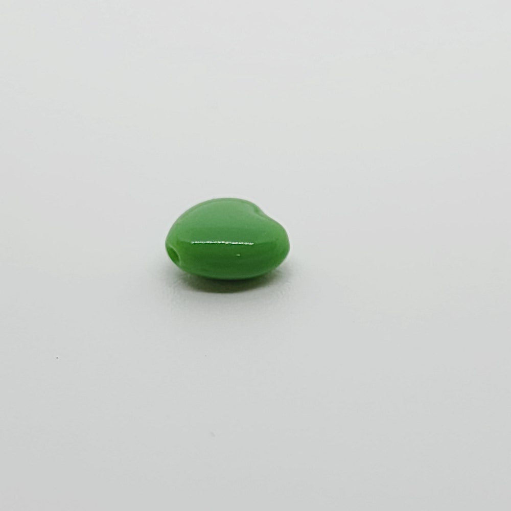 close up photo of one green opaque heart bead
