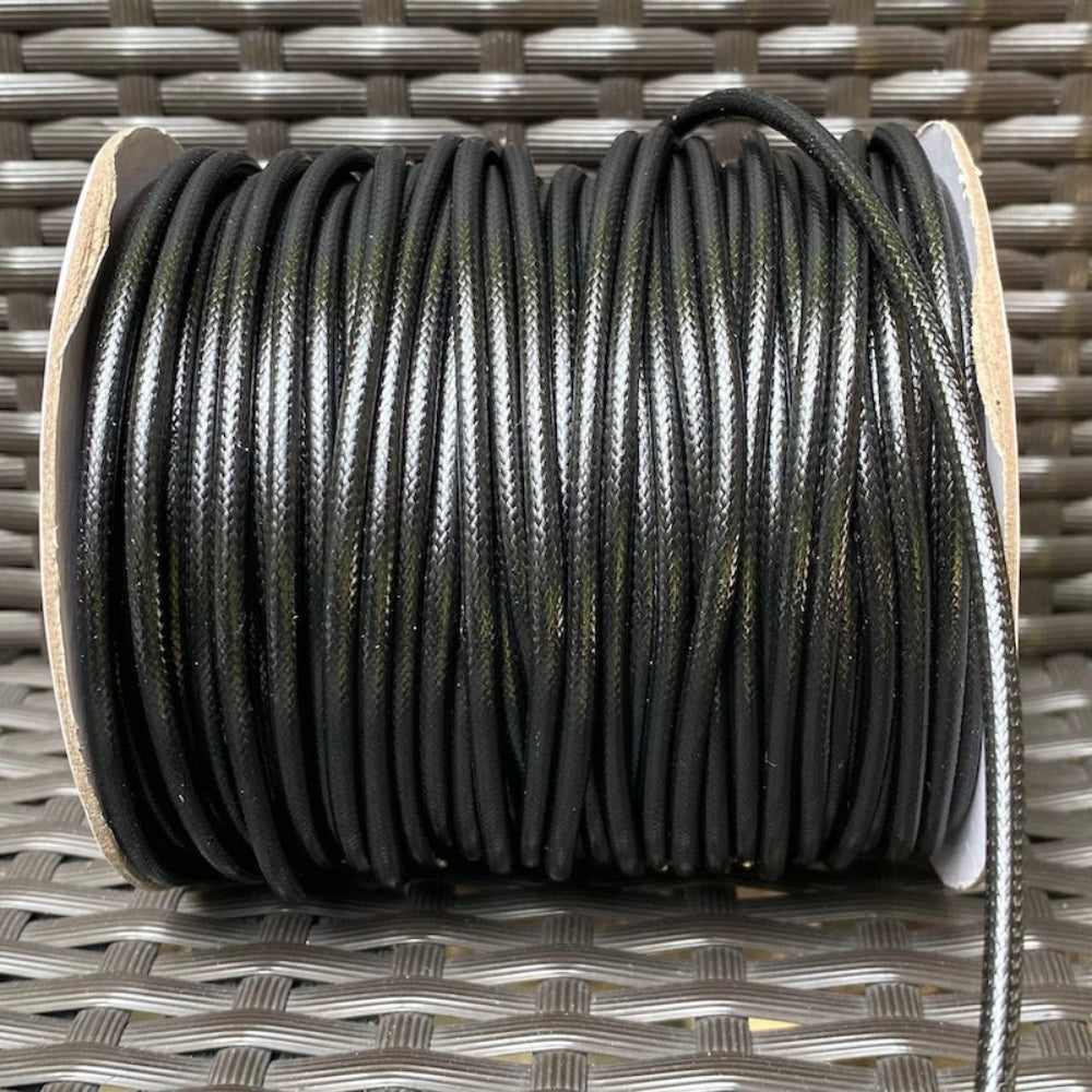 A spool of black waxed cord for crafting, displayed on a woven surface.