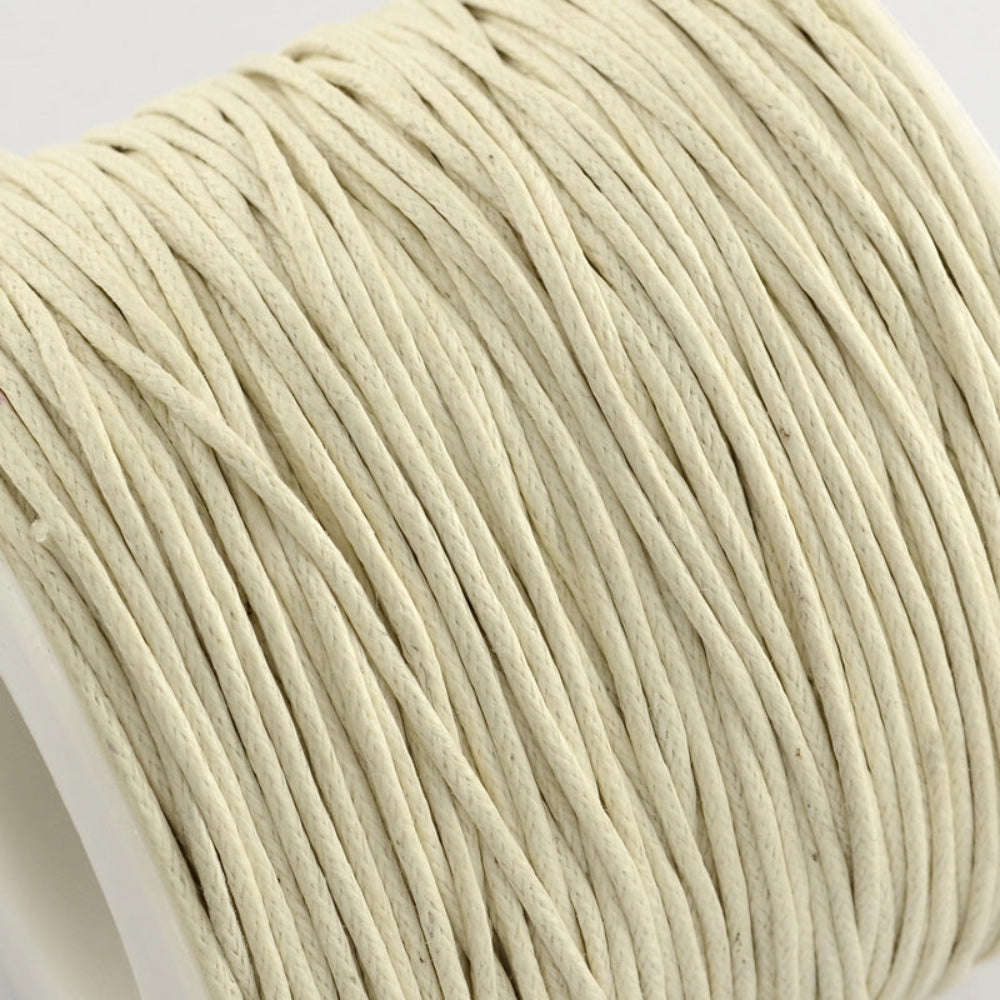 A spool of cream wax cotton cord used for crafting and jewelry making.