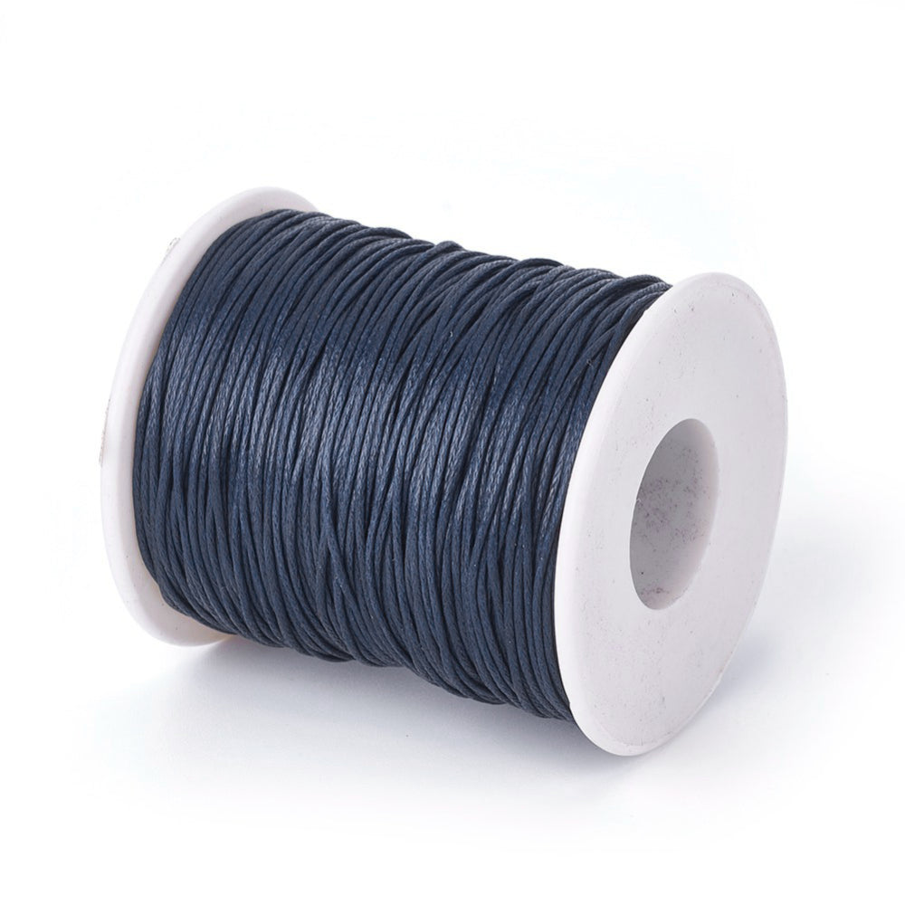 A spool of dark blue wax cotton cord used for crafting and jewelry making.