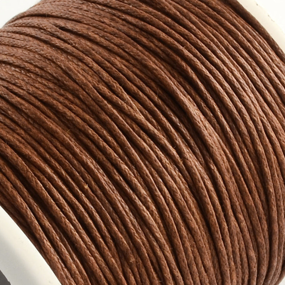 A spool of brown wax cotton cord used for crafting and jewelry making.