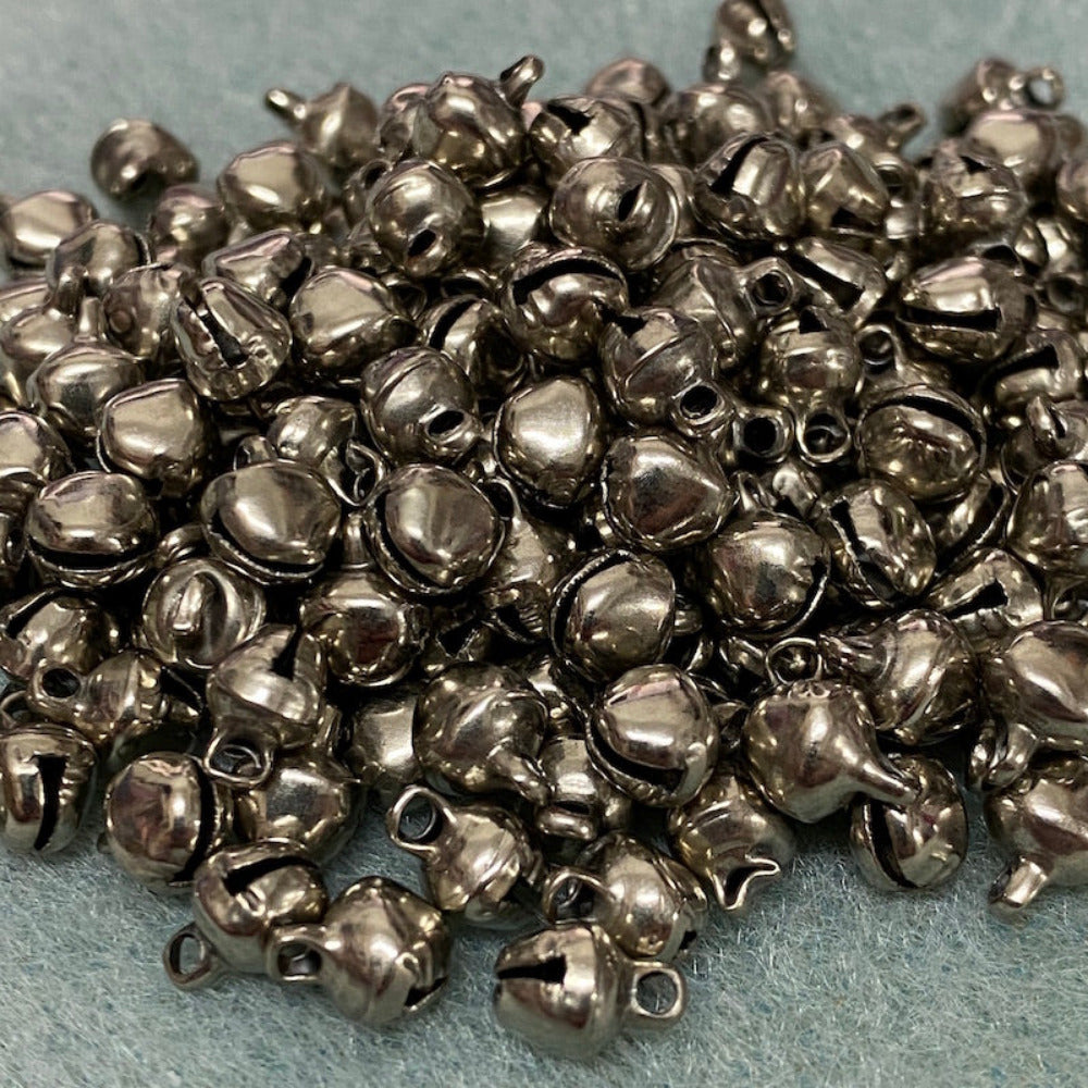 small metallic bells with loops on a textured surface for the purpose of making decorations and craft items