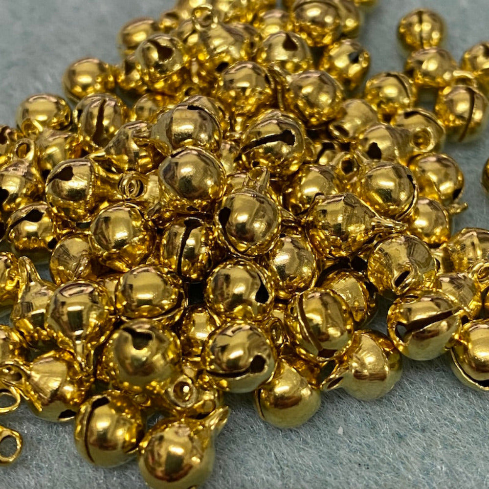 small metallic bells with loops on a textured surface for the purpose of making decorations and craft items