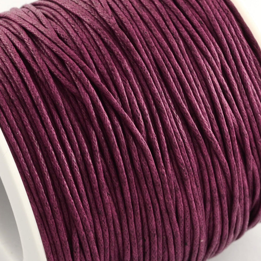A spool of medium red violet wax cotton cord used for crafting and jewelry making.