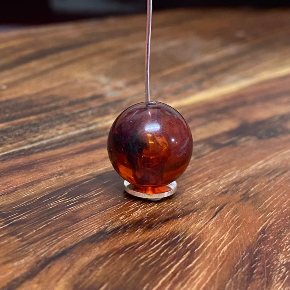 one round transparent amber colour beads displayed on a wood surface with visible holes for stringing jewelry and creating craft