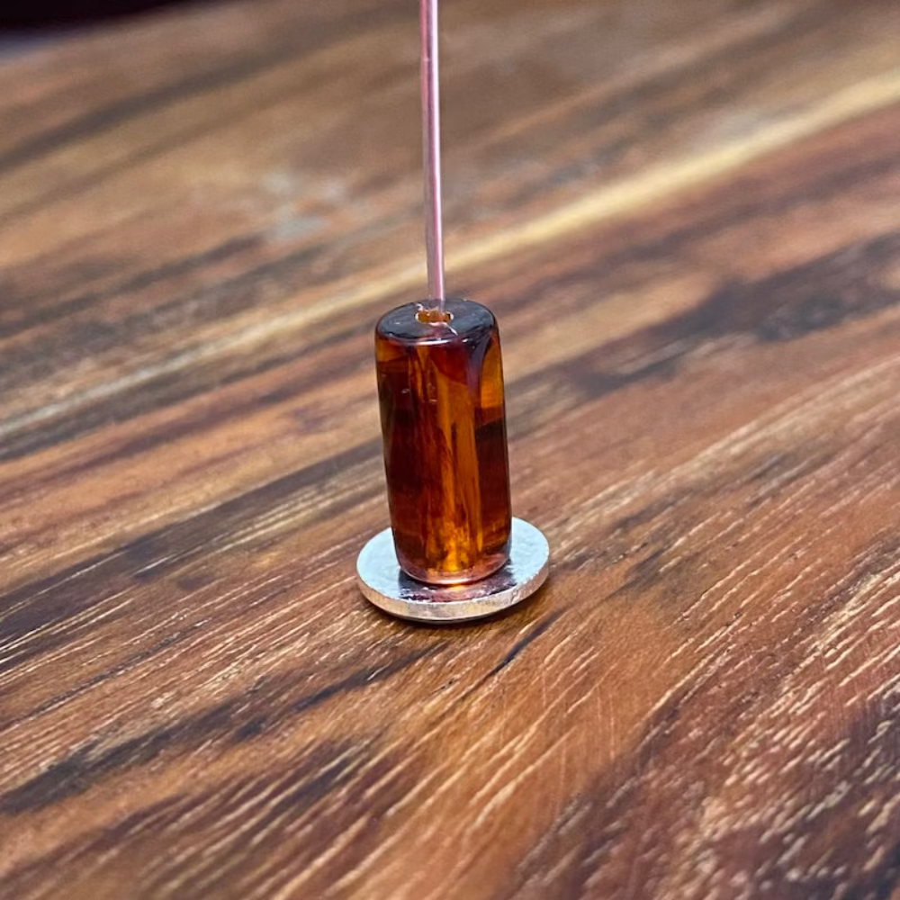 one transparent amber colour beads displayed on a wood surface with visible holes for stringing jewelry and creating craft