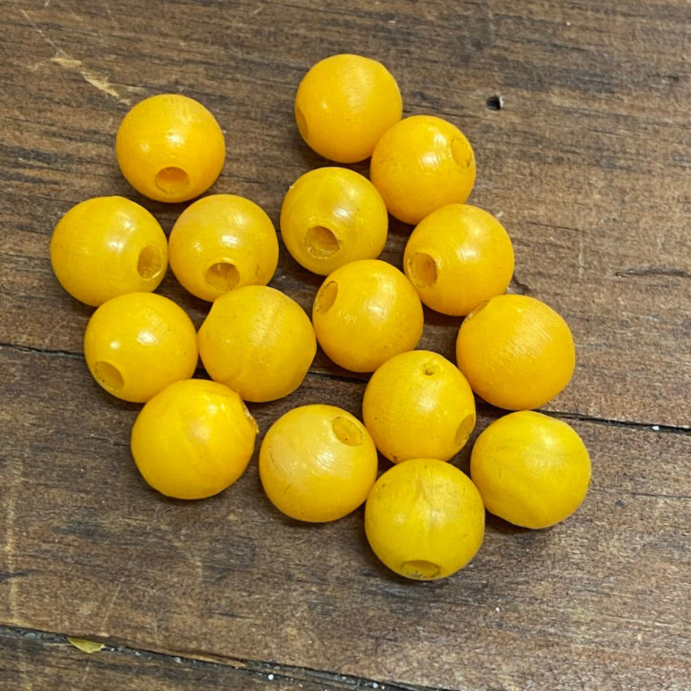 A collection of vintage phenolic amber beads in a buttery yellow colour showing large visible holes for the purpose of jewelry making and craft on a wood surface