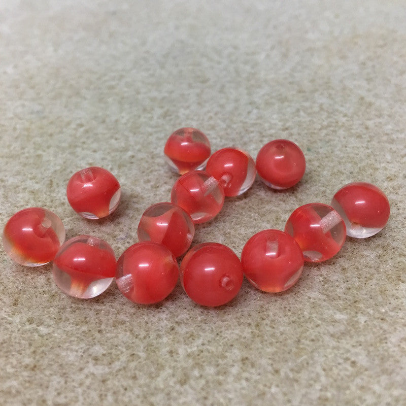 close up photo of a group of tomato red givre glass beads on a brown surface