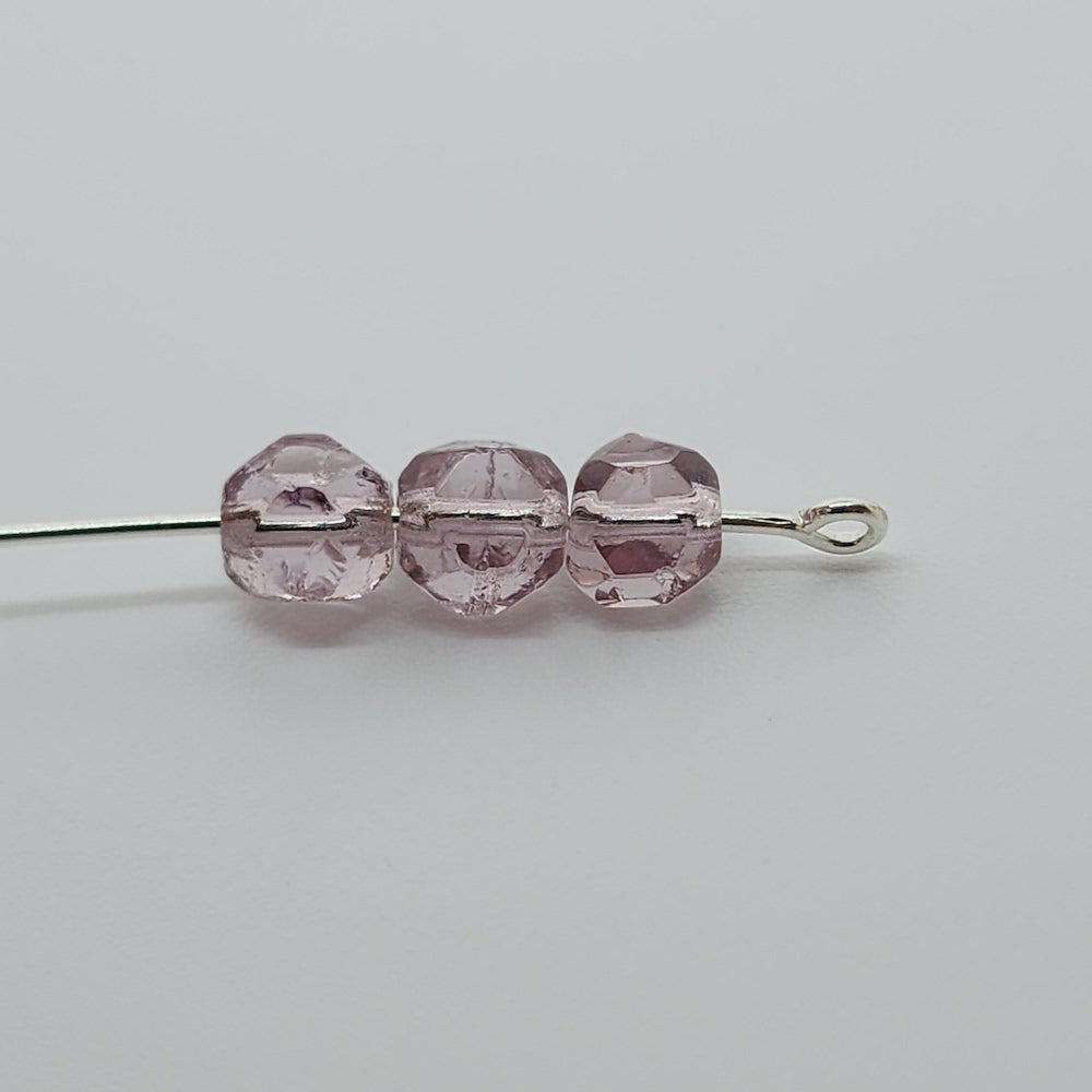 cut glass purple beads on a pin to show the shape on a grey background