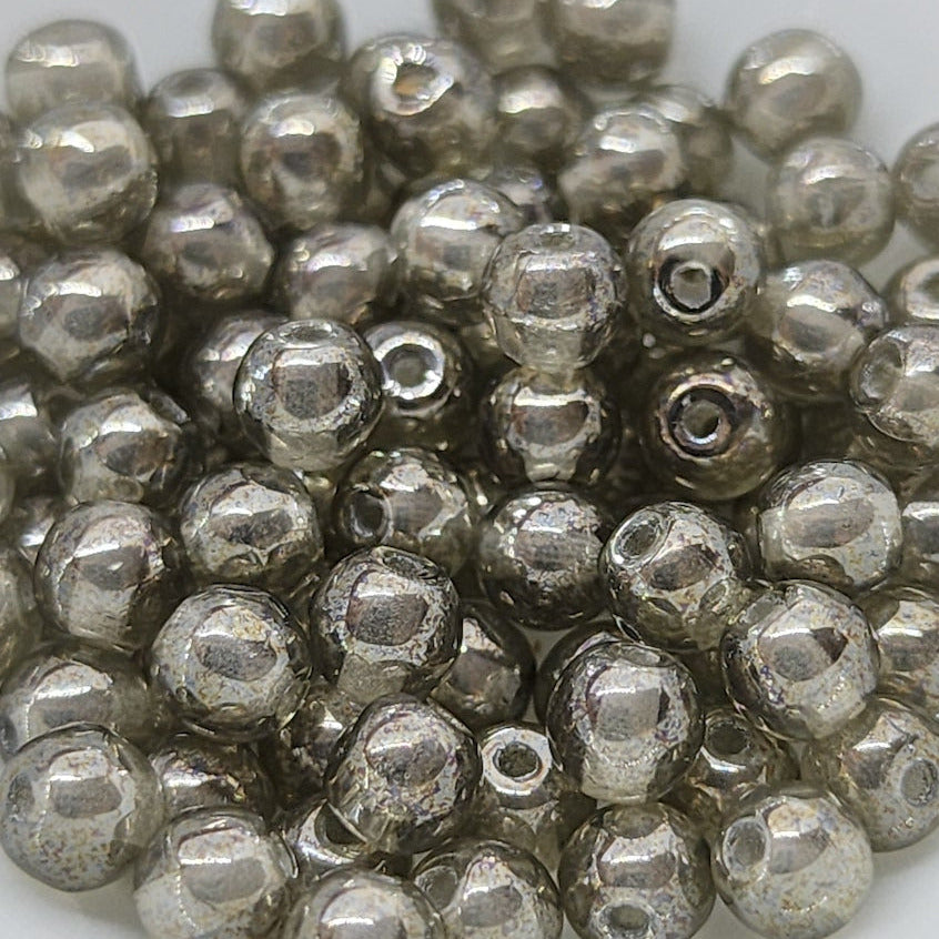 transparent grey beads with silver lustre arranged in a pile on a white background