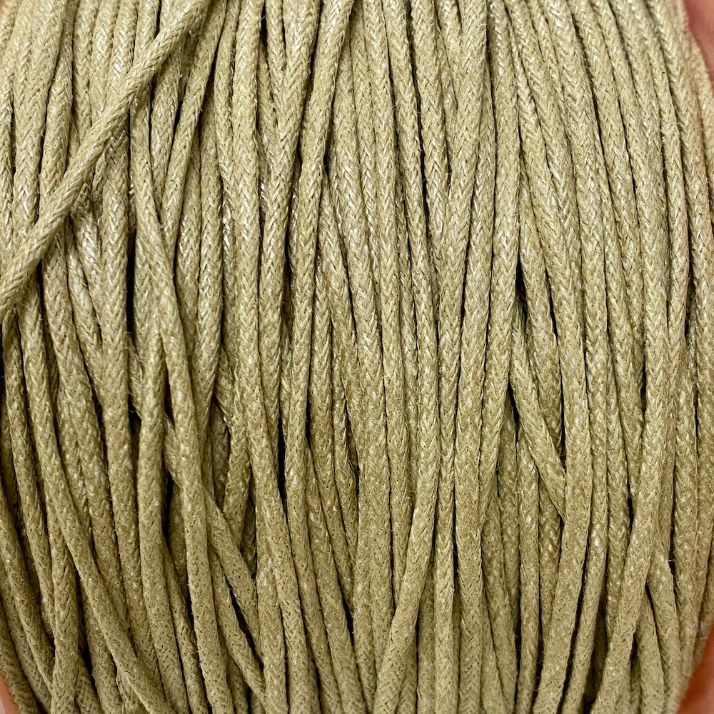 A spool of natural beige waxed cotton cord used for crafting and jewelry making.